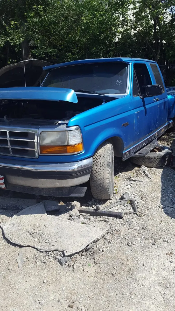Blue Ford F-150 with its hood up at an Indianapolis salvage yard -- complete used assemblies like these cost far less than bare new replacements