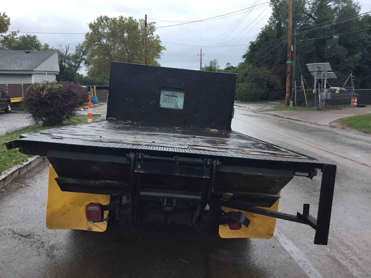 Flatbed tow truck staging a vehicle for intake at an Indianapolis salvage yard