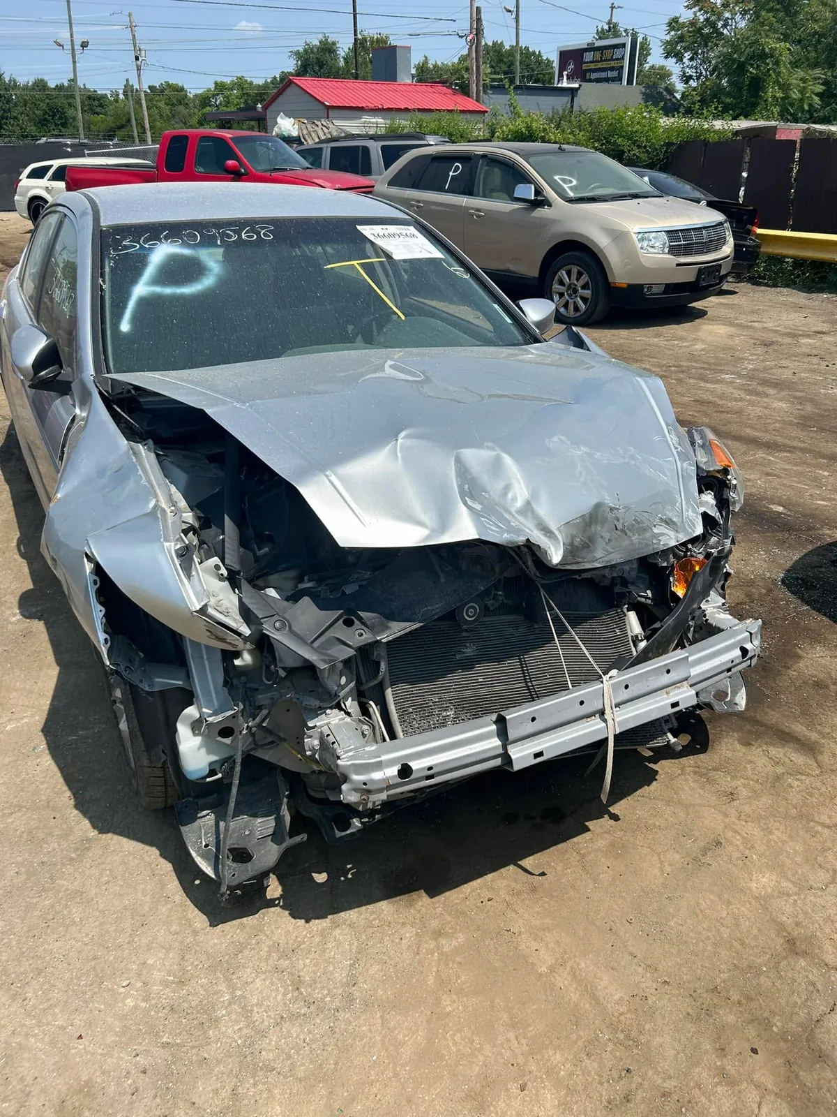 Damaged silver sedan marked for parts processing at an Indianapolis salvage yard