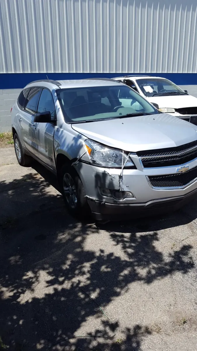 Front-end collision damage on a Chevrolet Traverse donor vehicle -- its undamaged doors, fenders, and lights become exact-fit used OEM parts