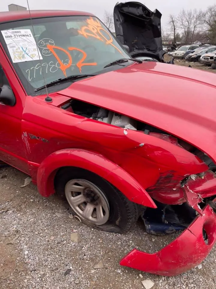 Damaged Ford Ranger marked with inventory codes at the salvage yard, ready for parts assessment